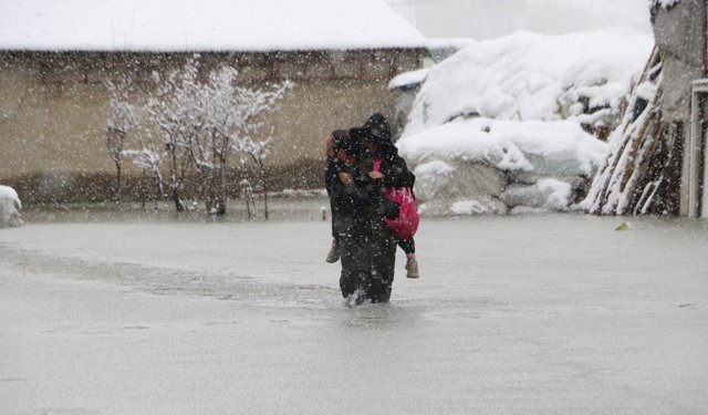 Hakkari'de biriken su nedeniyle çocuklarını sırtında taşıyor