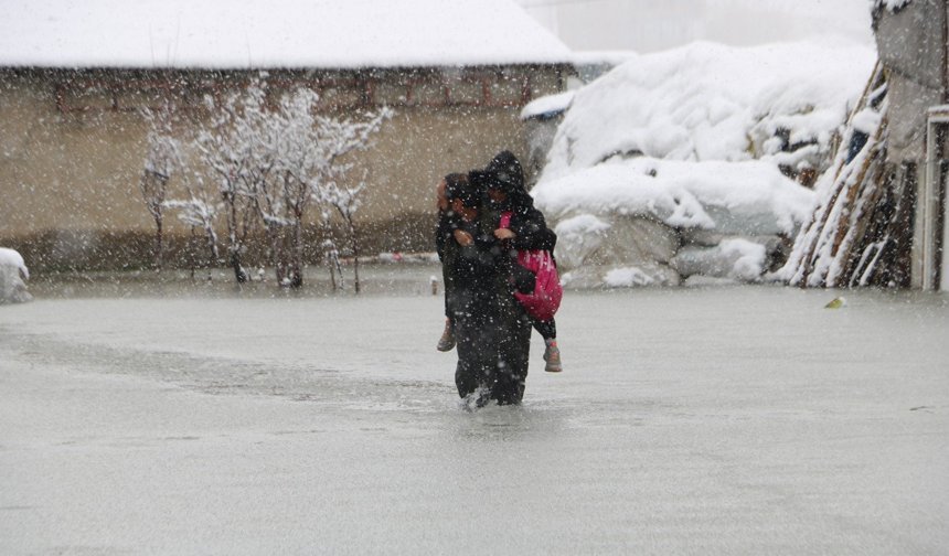 Hakkari'de biriken su nedeniyle çocuklarını sırtında taşıyor